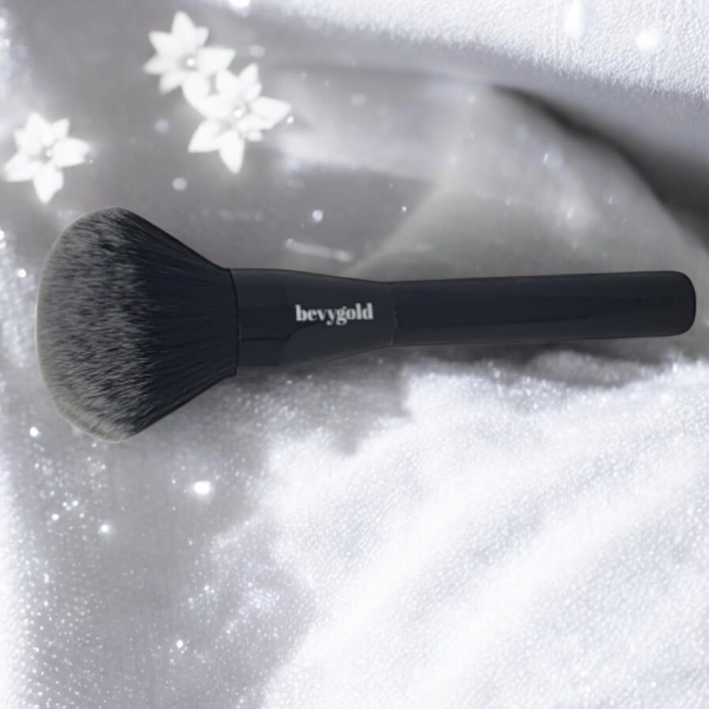 Triangular-shaped kabuki brush with a long, glossy black handle. Featuring fluffy and soft bristles, ideal for applying bronzer, setting powder, and loose powder on both the face and body.