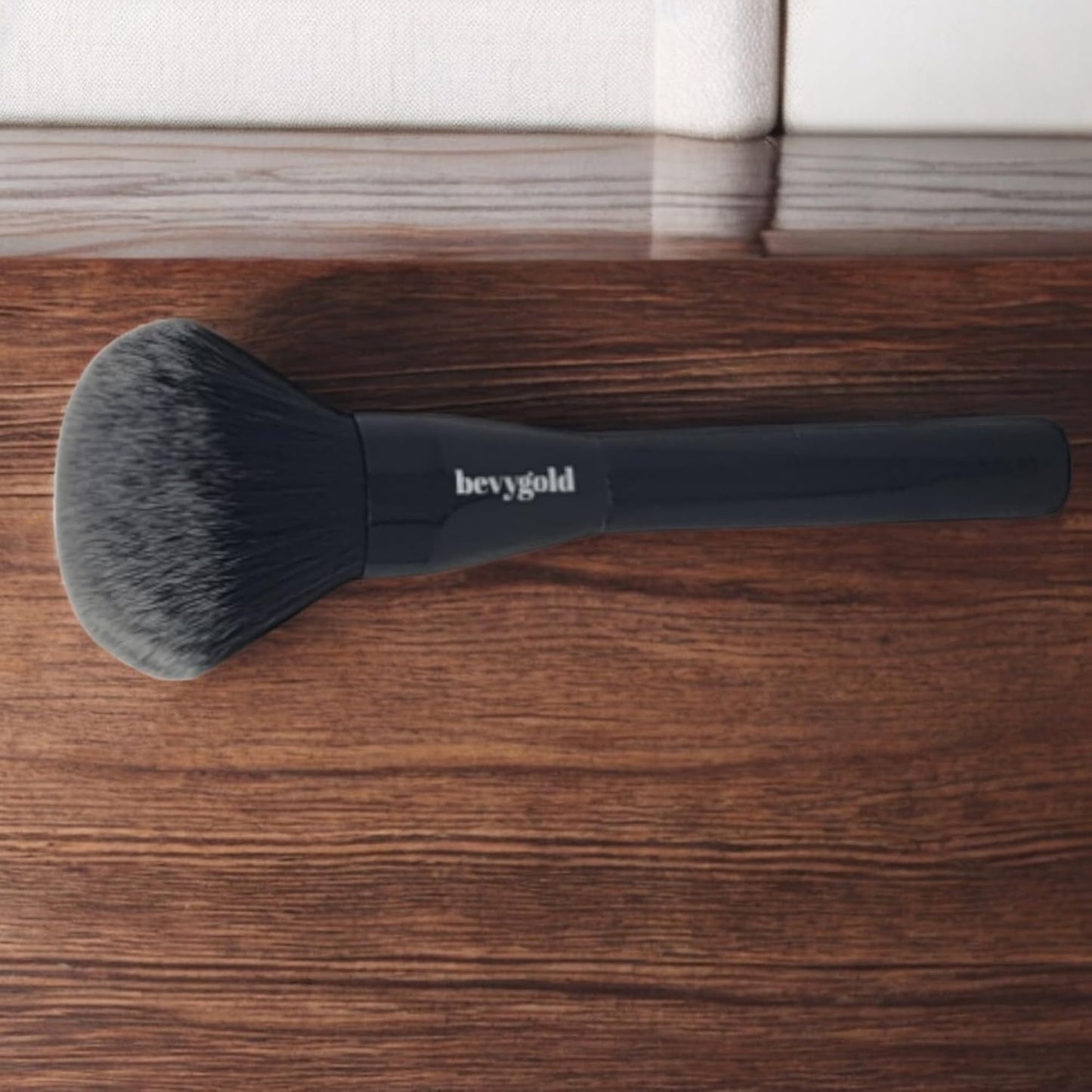 Triangular-shaped kabuki brush with a long, glossy black handle. Featuring fluffy and soft bristles, ideal for applying bronzer, setting powder, and loose powder on both the face and body.